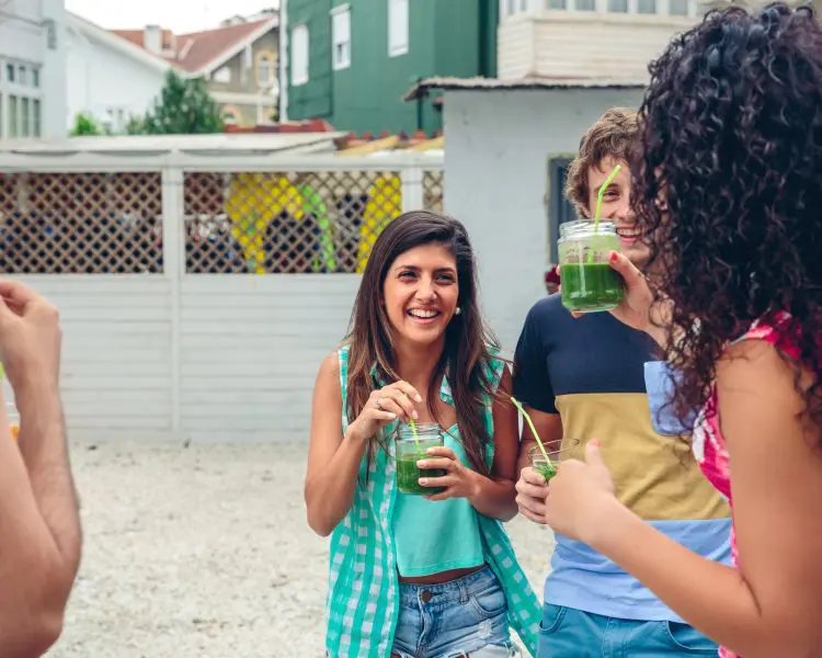 Group of people smiling drinking green smoothies