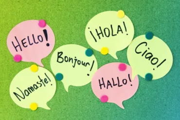 Speech bubble post it notes on a cork board with greetings written in different languages