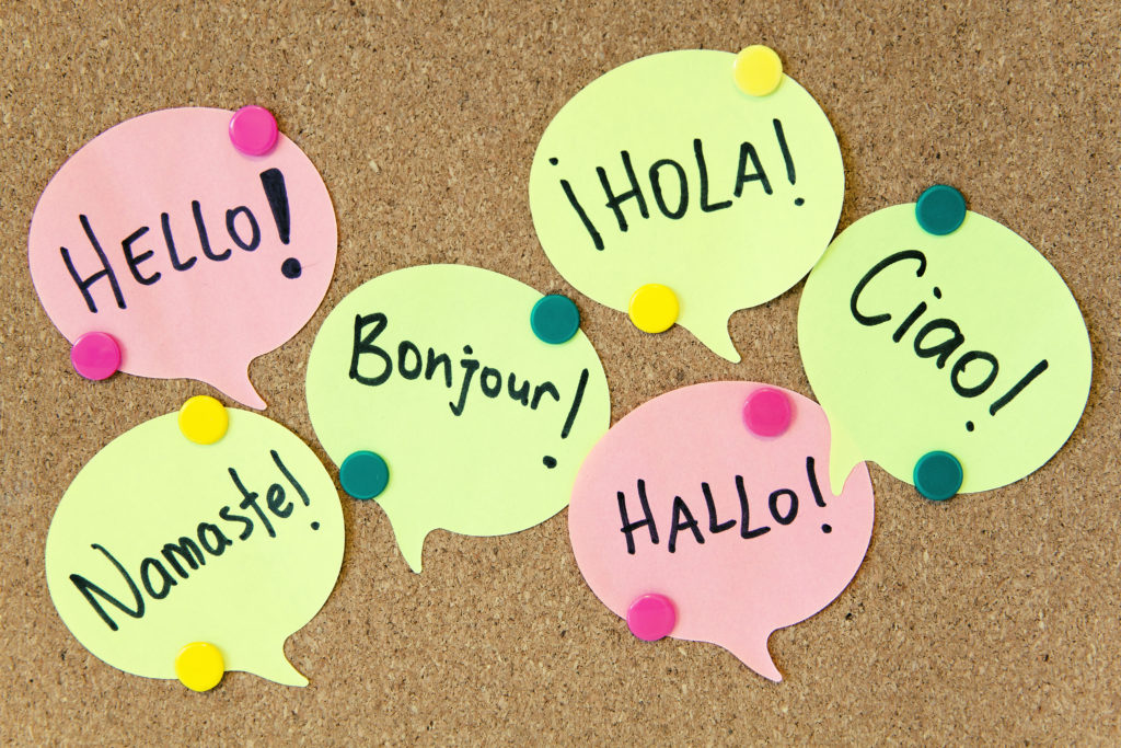 A cork board with paper speech bubbles pinned to it, saying 'hello' in different languages