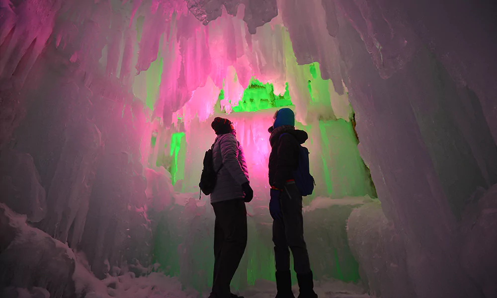 two people standing next to large ice structure