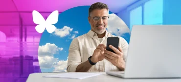 man in an office using a phone and laptop