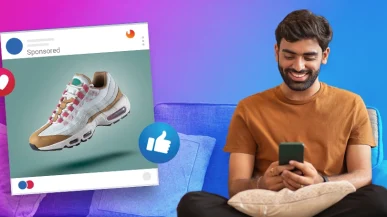 A man looking at his phone with an example of Facebook ad next to him