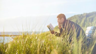 man reading book near some cliffs