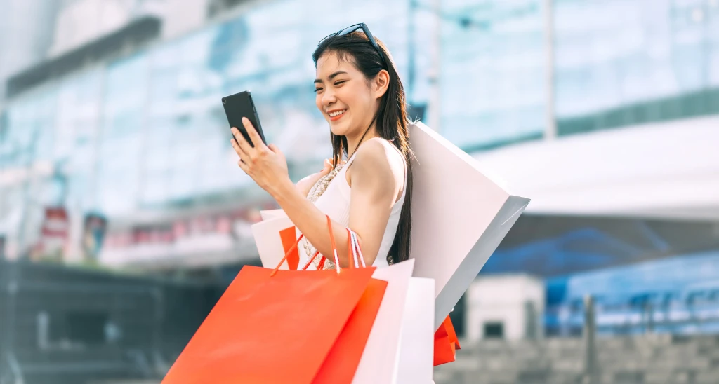 A Thai woman checking her phone whilst shopping